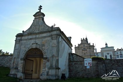 Brama wjazdowa a w oddali zabudowania klasztorne.